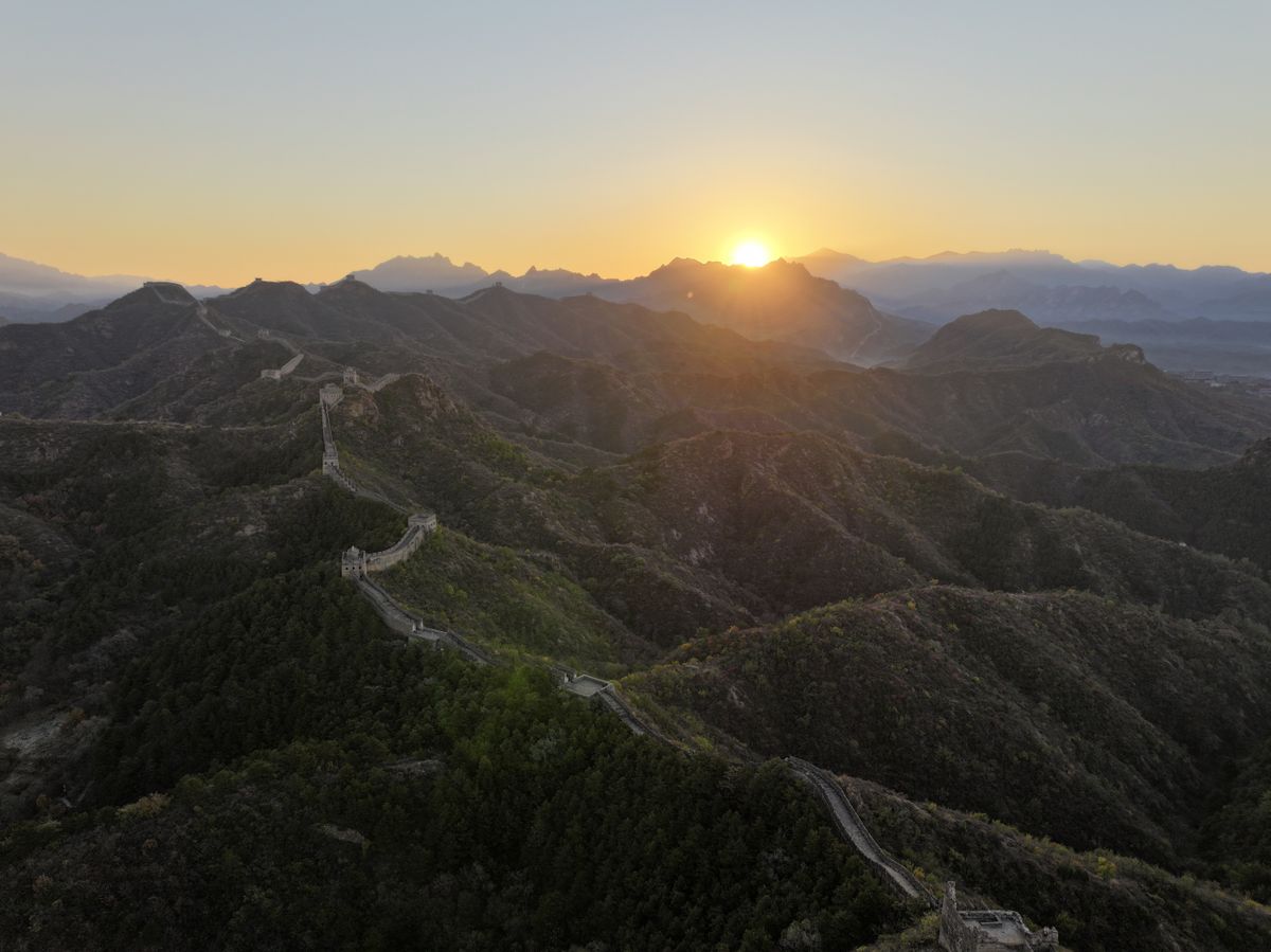 The Great Wall of China snaking over forested ridges