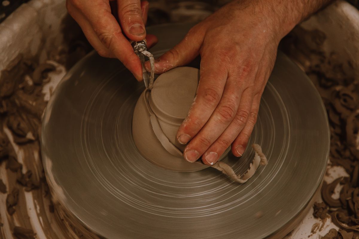 Hands shaping clay on a pottery wheel